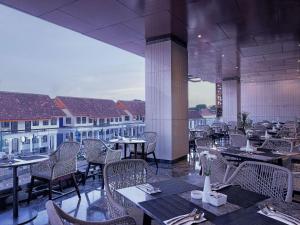 a restaurant with tables and chairs and a view of buildings at Royal Malioboro by ASTON in Yogyakarta