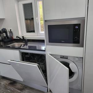 une cuisine équipée d'un lave-linge, d'un évier et d'un micro-ondes dans l'établissement Nandos Apartement, à Costa da Caparica 7 autres photos
