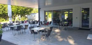 an outdoor patio with tables and chairs and windows at Camping de l'Ill in Mulhouse