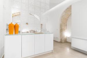 a white kitchen with orange vases on a cabinet at Casa Zummo Ortigia Luxury Apartment in Siracusa