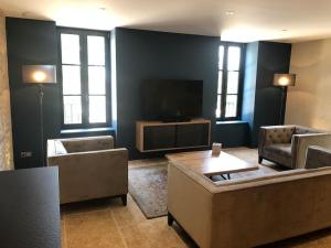 a living room with couches and a flat screen tv at La Maison Des Vignes ***** in Volnay