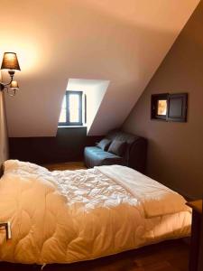 a bedroom with a bed and a couch in a attic at La Maison Des Vignes ***** in Volnay