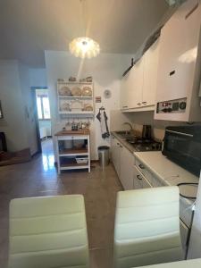 cocina con armarios blancos, mesa y sillas en Villaggio Riviera - Agenzia Cocal, en Caorle