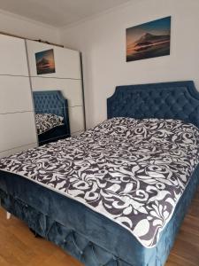 a bedroom with a blue bed with a black and white comforter at Helena apartman in Ocka Gora