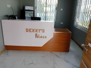 a desk with a sign that reads devils palace at Dexxy's Palace Hotel in Koforidua