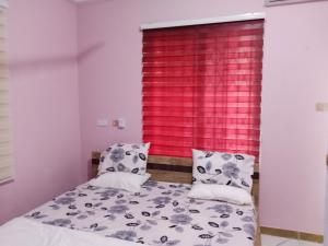 1 dormitorio con cama y ventana roja en Dexxy's Palace Hotel, en Koforidua