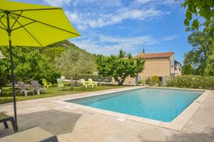 a pool with an umbrella and chairs and a house at Gîte La loge 142 route de CARPENTRAS 84210 VENASQUE in Venasque