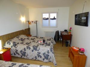 a bedroom with a bed and a desk and a window at Auberge des Avenières in Les Avenières