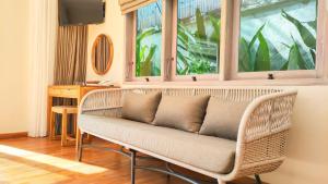 a wicker couch in a room with a window at Seminyak Square Hotel And Villas in Seminyak