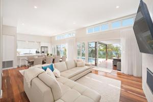 a living room with a white couch and a kitchen at 43 Gawul Circuit Corlette in Corlette