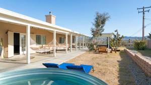 a house with a swimming pool and some blue chairs at Hillside Desert House - Hot Tub, Fire Pit and BBQ! home in Yucca Valley