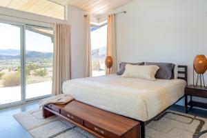 1 dormitorio con cama y ventana grande en Las Alas del Sol- A Desert Architectural Gem home, en Joshua Tree