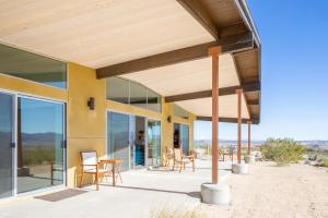 un patio con sillas y mesas en un edificio en Las Alas del Sol- A Desert Architectural Gem home, en Joshua Tree