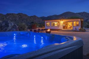 een huis met een zwembad in de nacht bij La Luna Azul - Privacy in the Boulders with Hot Tub & Fire Pit home in Joshua Tree