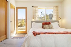een slaapkamer met een groot wit bed en een raam bij La Luna Azul - Privacy in the Boulders with Hot Tub & Fire Pit home in Joshua Tree