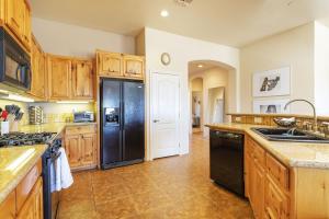 a kitchen with a black refrigerator and wooden cabinets at Horizon House - Hot Tub, Fire Pit & BBQ - Adobe in JT home in Joshua Tree
