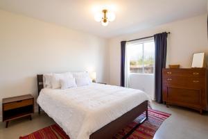 a bedroom with a bed with a dresser and a window at The RockHopper - Hot Tub, Fire Pit & Walk to Downtown JT! home in Joshua Tree