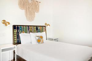 a bedroom with a white bed and a cross on the wall at Back Haus - Views, Dark Skies and Fire Pit! home in Joshua Tree