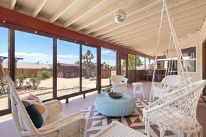 een veranda met schommelstoelen en een tafel bij Euphorbia House - Fire Pit, Ping Pong, Tether Ball & Dark Skies home in Yucca Valley