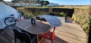een houten terras met een tafel, stoelen en een fiets bij Zen et Mer in Le Grau-du-Roi