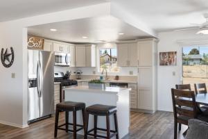 a kitchen with white cabinets and a kitchen island with bar stools at Horseshoe House - Hot Tub, BBQ and Fire Pit! home in Joshua Tree +9 photos