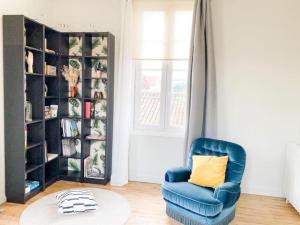 ein Wohnzimmer mit einem blauen Stuhl und einem Bücherregal in der Unterkunft Appartement lumineux centre Cognac avec terrasse in Cognac