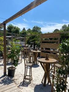 a patio with tables and chairs and a pergola at CAMPING Bassin Arcachon - LES GOELANDS in Arès
