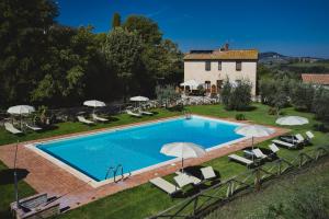 - une piscine avec des chaises et des parasols en face d'une maison dans l'établissement Podere Sant'Elena, à San Gimignano