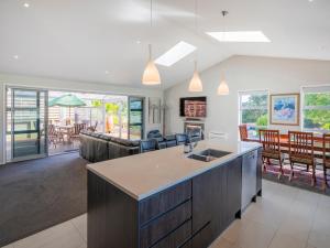 a kitchen and living room with a couch and a table at Relax on Roseberry - Whitianga Holiday Home in Whitianga