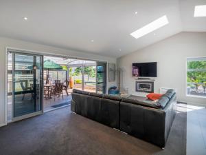 a living room with a leather couch and a dining room at Relax on Roseberry - Whitianga Holiday Home in Whitianga