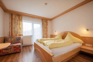 a bedroom with a bed and a chair and a window at Haus Hubertus in Mieders