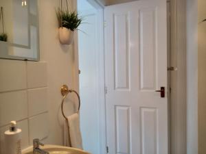 a bathroom with a white door with a potted plant at West Looe Downs in Looe