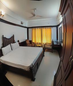 ein Schlafzimmer mit einem großen Bett und einem Schreibtisch in der Unterkunft Vyshak International in Payyannūr