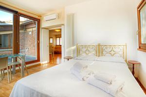 - une chambre avec un grand lit blanc et des serviettes dans l'établissement Attic Luna Blu, à Sienne