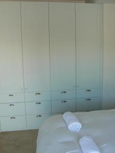 a bedroom with white cabinets and a bed with two towels at The Don Lodge in Amanzimtoti