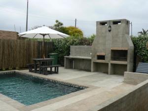 a patio with a table and an umbrella next to a pool at The Don Lodge in Amanzimtoti