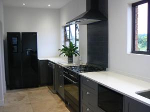 a kitchen with a stove and a black refrigerator at The Don Lodge in Amanzimtoti