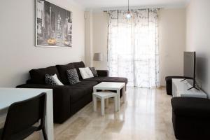een woonkamer met een zwarte bank en een tafel bij Apartamento Málaga Jalón in Málaga
