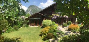 a garden in front of a house with mountains in the background at Chalet les Chouettes in Thônes