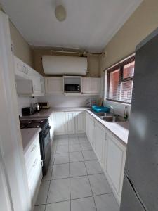 a small kitchen with white cabinets and a sink at 3 Marilyn Court in Scottburgh