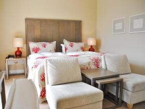 a bedroom with a bed and a couch and a chair at Strandhotel Miramar in Timmendorfer Strand