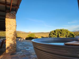 a hot tub on a patio with a view of the desert at Ribboksfontein Guest Farm in De Rust
