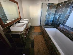 a bathroom with a tub and a sink and a mirror at Ribboksfontein Guest Farm in De Rust