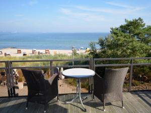 einen Tisch und Stühle auf einem Balkon mit Strandblick in der Unterkunft Strandhotel Miramar in Timmendorfer Strand