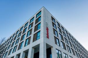 un grand bâtiment avec un panneau rouge sur lui dans l'établissement IntercityHotel Berlin Airport BER Terminal 1 & 2, à Schönefeld