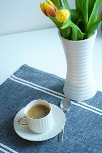 a cup of coffee on a plate next to a vase with flowers at Inn Tourist Hostel in Helsinki