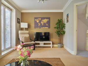 uma sala de estar com uma televisão, um sofá e uma cadeira em Curb Properties - Gorgeous 3 Bedroom House Close To Town Centre em Cheltenham