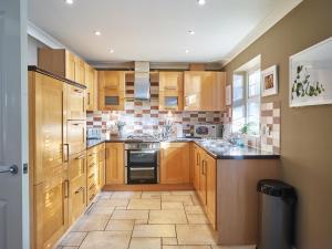 a kitchen with wooden cabinets and black appliances at Curb Properties - Gorgeous 3 Bedroom House Close To Town Centre in Cheltenham