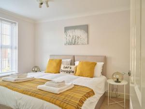 a white bedroom with a bed with towels on it at Curb Properties - Gorgeous 3 Bedroom House Close To Town Centre in Cheltenham