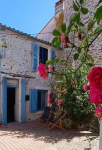 un bâtiment avec une porte bleue et des roses roses dans l'établissement Bienvenue au Cocon Chaumois - Les Sables d'Olonne - La Clé Chaumoise, à La Chaume